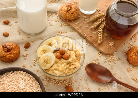 Spelt porridge with slices of banana and almonds in a glass bowl. Stock Photo