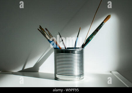 Tin can with paint brushes closeup on white wall background Stock Photo