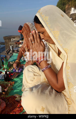 Devout Hindu pilgrim prays on the ghats of the sacred river Narmada in Maheshwar, India Stock Photo