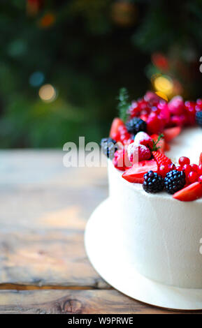 Christmas Cake decorated with berries by the Christmas tree Stock Photo