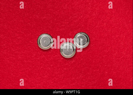 three lithium button cell battery, round batteries on a red background Stock Photo