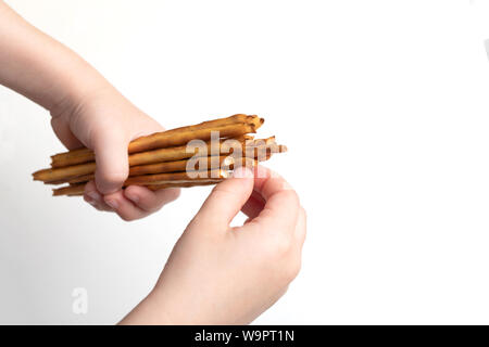 children hands hold  salted bread bread sticks or straws on a white background Stock Photo
