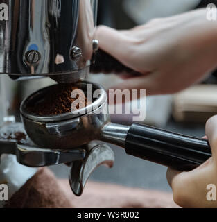 Manual coffee bean grinder. Ground coffee powder with both hands. Coffee powder is in the handle of the coffee machine. Stock Photo