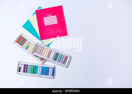 Flatlay childrens and school accessories notebooks and colored pencils over white background - Back to school concept. Copy space. Place for text. Stock Photo