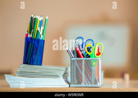 Stack of notebooks, colorful drawing pencils and stationery arrangement on copy space background. Stock Photo