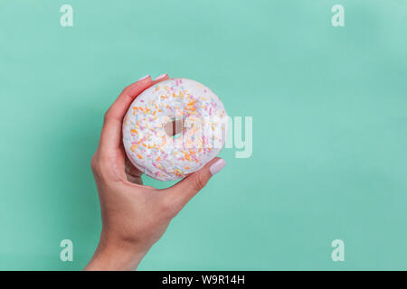 Woman's hand holding delicious donut on pastel backround Stock Photo