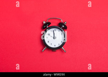 Small vintage alarm clock on the red background Stock Photo