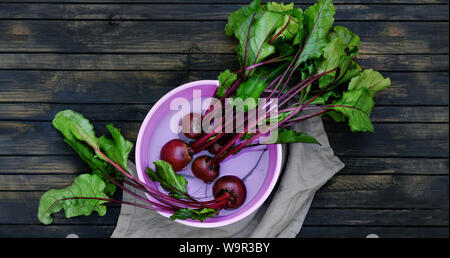 Beets in rinsing. beetroot is a helthy food and is rich in antioxidants and vitamins. Roots in a water bowl on a dark wood table. Stock Photo