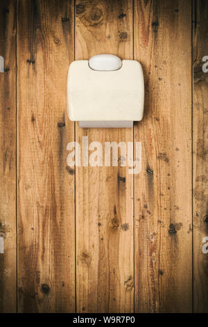 Disgust concept. Toilet tissue holder with empty roll on very dirty outhouse wall Stock Photo