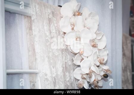 Closeup shot of white lily flowers indoors on a white window blinders Stock Photo