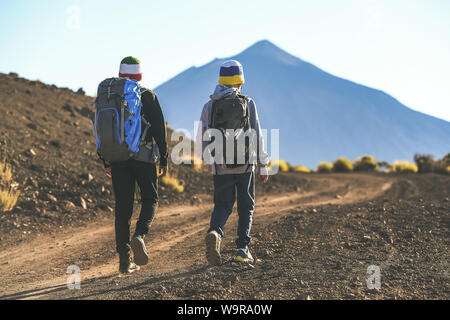 Two young boys walking on a path toward the volcano Teide A couple of tourist child climbing mountain together Italian and Canary island flag on wool Stock Photo