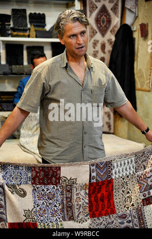 Carpets seller showing products, Iran Stock Photo