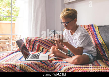 Beautiful blonde teen reading new trend stories online on smartphone Technology addicted young boy watching social video at home Teenager communicate Stock Photo