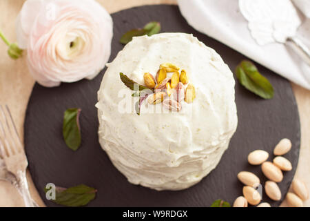 Delicate airy pistachio cake with frosting on black stone plate Stock Photo