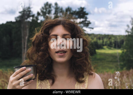 Beautiful young curly-haired red-haired girl with a mug  Stock Photo