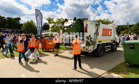 Wheelie bin emptied into waste collection dustbin lorry, bags of rubbish & refuse collectors working at busy venue - Great Yorkshire Show, England, UK Stock Photo