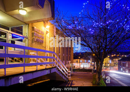 Exterior & entrance doorway of Baildon village Branch Library illuminated at night & Christmas fairy lights lit on tree - West Yorkshire, England, UK. Stock Photo