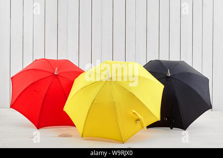 Three umbrellas on floor near white wooden background with space for design Stock Photo