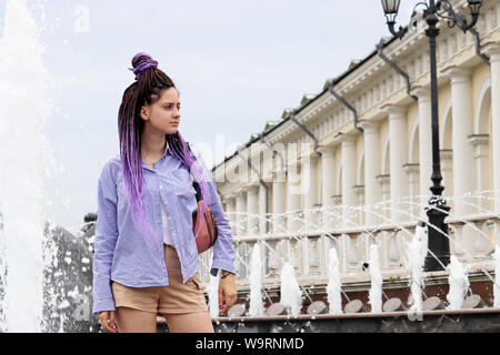 Girl with dreads posing on background of splashing fountain Four Seasons on Manezhnaya square Stock Photo