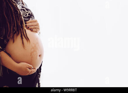 Harmless henna floral drawing art on boho pregnant woman tummy, beautiful maternity concept. White light copy space. Stock Photo