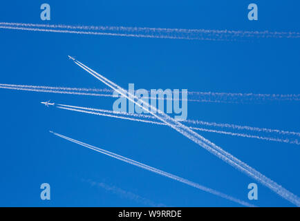 A lot of passenger airplanes on the air, busy air traffic, traveling high season starts concept. White planes against blue sky.  Photo manipulation. Stock Photo