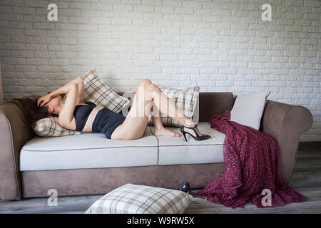 Woman lying on a sofa with no makeup and being dissapointed about her body. Stock Photo