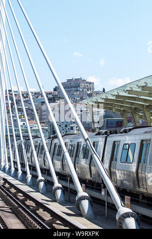 A metro train docked at the station at the suspension bridge over the Golden Horn. In the background the historical administrative building for tunnel Stock Photo