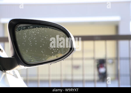 The side mirror of the car with drops water on the glass. Car rearview mirror with droplets. Stock Photo