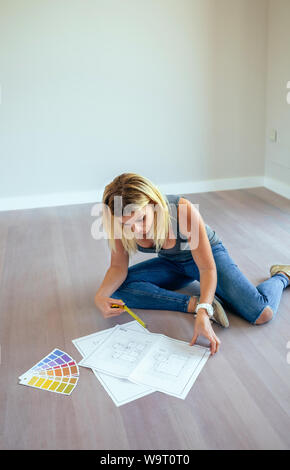 Girl looking house plans sitting on the floor Stock Photo