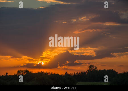 Sun rays and the sun behind the clouds. Nowiny, Poland Stock Photo