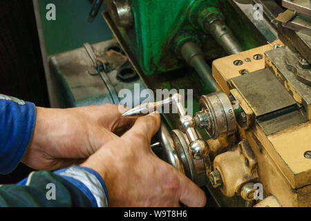 working on turnind lathe with manual control, hands of turner hold the handles of the carriage Stock Photo