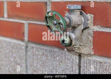 Old corroded outdoor water spigot, faucet, or tap leaking, dripping water and needing repair Stock Photo