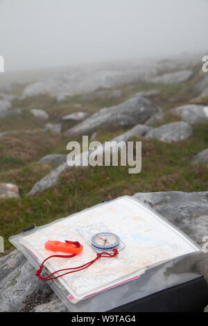 Close-Up Of Navigational Compass With Whistle And Map on a Scottish hill in the fog. Stock Photo