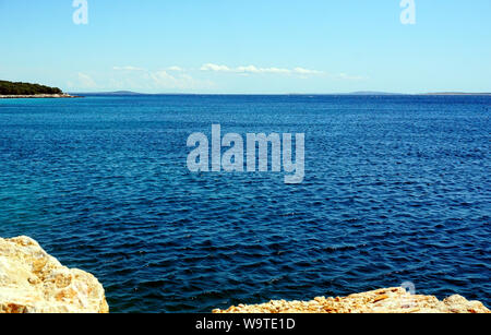 Nature background with blue wavy sea surface and horizon line, view from the rocky coast Stock Photo