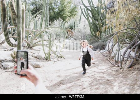 Mother photographing her daughter running in the desert, Palm Springs, California, United States Stock Photo