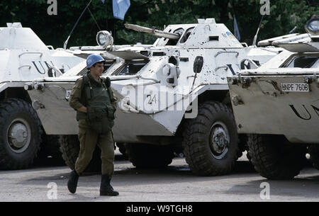 9th May 1993 During the Siege of Sarajevo: a Ukrainian soldier passes BTR-80 APCs parked in the parade ground of Tito Barracks. As part of the United Nations Protection Force (UNPROFOR), they are about to depart to offer protection to the Bosnian Muslim enclave of Žepa, 40 kilometres east of Sarajevo. Stock Photo