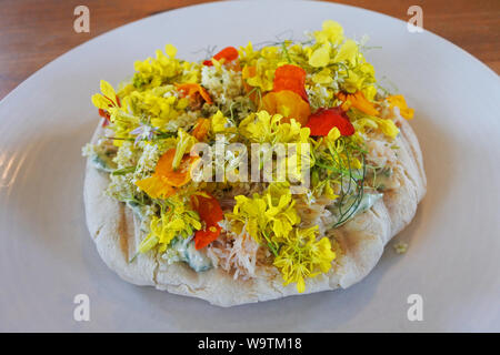 Studio shot of fresh crab mixed with mayonnaise on flat bread topped with a mixture of wild flowers - John Gollop Stock Photo