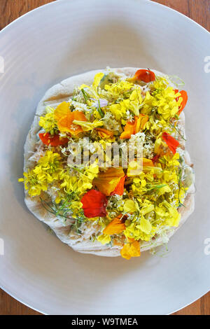 Studio shot of fresh crab mixed with mayonnaise on flat bread topped with a mixture of wild flowers - John Gollop Stock Photo