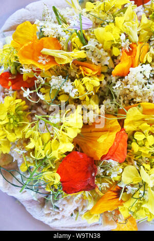 Studio shot of fresh crab mixed with mayonnaise on flat bread topped with a mixture of wild flowers - John Gollop Stock Photo