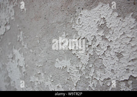 Light grey paint peeling off dark grey stone wall Stock Photo