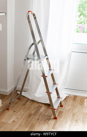 Part of the home or hotel interior, iron stepladder against the background of a window with white curtains Stock Photo