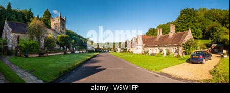 Dorchester, Dorset, UK - August 26, 2012: Summer sun shines on the traditional cottages and parish church of Milton Abbas in Dorset. Stock Photo