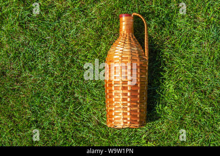 Rattan wine bottle laying on green grass lawn , pic nic concept Stock Photo
