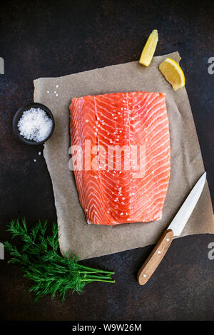 Top view of fresh raw salmon fillet with dill, sea salt and lemon on a table for cooking. Recipe for ketogenic or paleo diet. Stock Photo