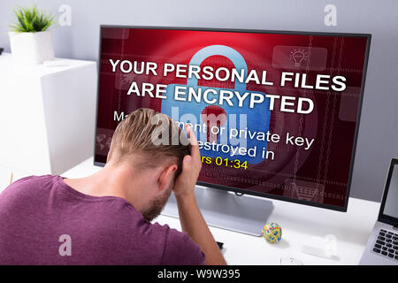 Worried Businessman At Computer With Ransomware Word On The Screen At The Workplace Stock Photo