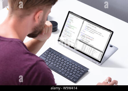 Man Programming Code On Laptop Computer In Office Stock Photo
