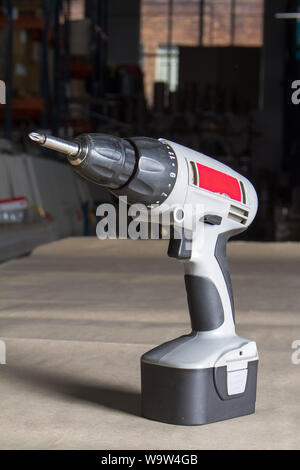 Gray electric drill ready to work stands on light wooden surface, selective focus Stock Photo