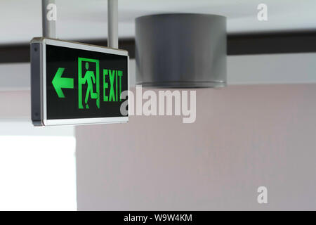 Side view of a green glowing sign with the words Exit and running man, selective focus Stock Photo