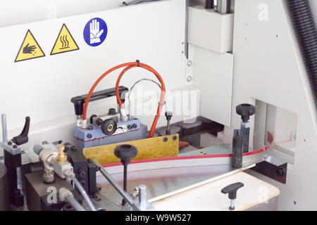 Close up mechanism of single sided automatic edge banders in a private furniture workshop, selective focus Stock Photo