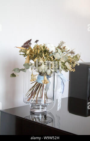 Bouquet of dried flowers in a glass vase with reflection on the surface of a mirrored black table, copyspace Stock Photo